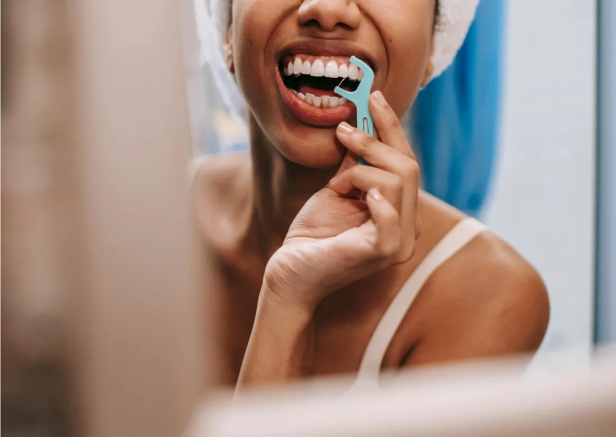 Woman flossing her teeth while following oral care instructions after a fluoride treatment.