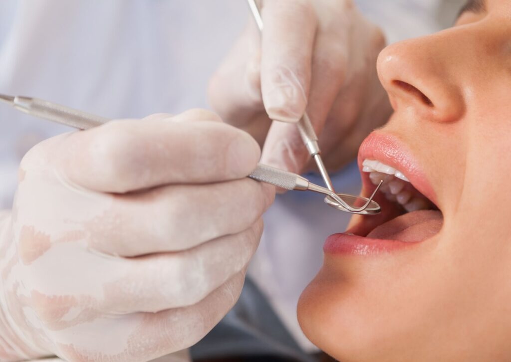 Dentist examining a patient's tooth before placing a dental crown during a routine restorative dental appointment.