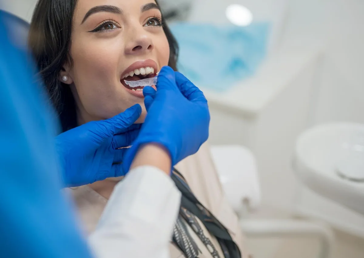 Orthodontist fitting a clear retainer for a patient while discussing retainer cost and aftercare.