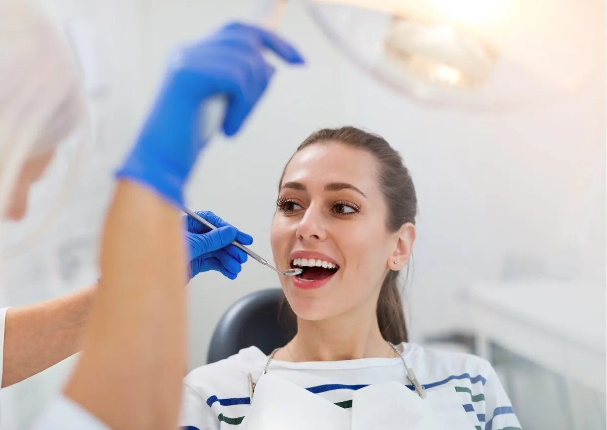 Dentist examining a patient’s teeth while discussing dental crown types, treatment options, and cost.