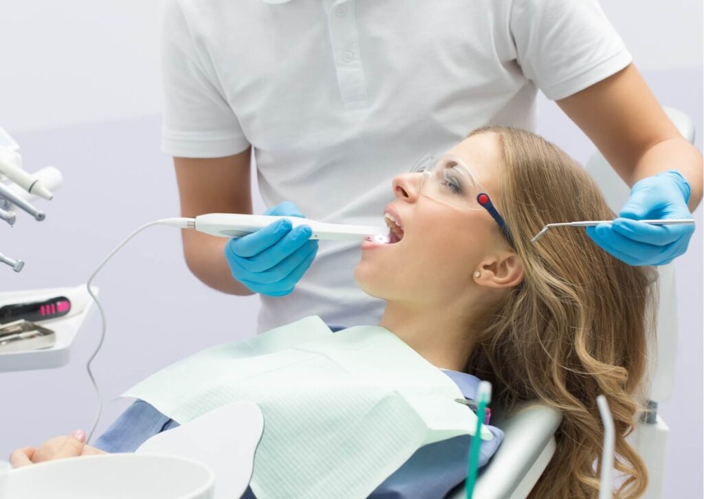 Dentist examining a patient's tooth for signs of infection using an intraoral camera during a dental exam.