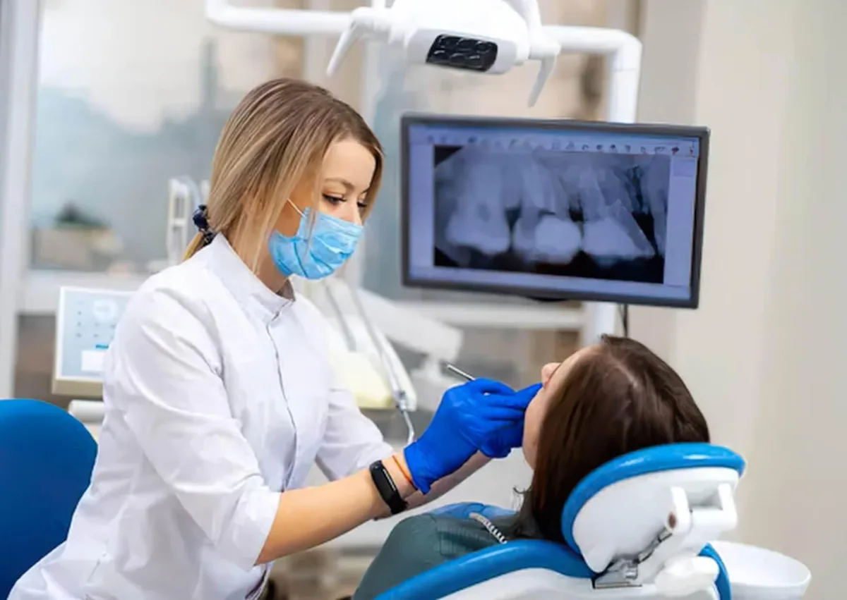 Dentist examining a patient’s teeth and X-rays while discussing affordable dental implant options.