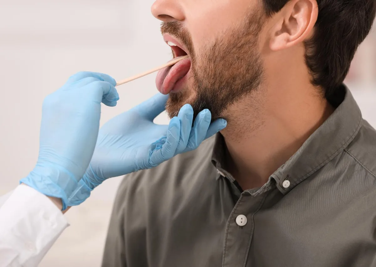 Healthcare professional examining a patient’s tongue for signs of oral thrush.