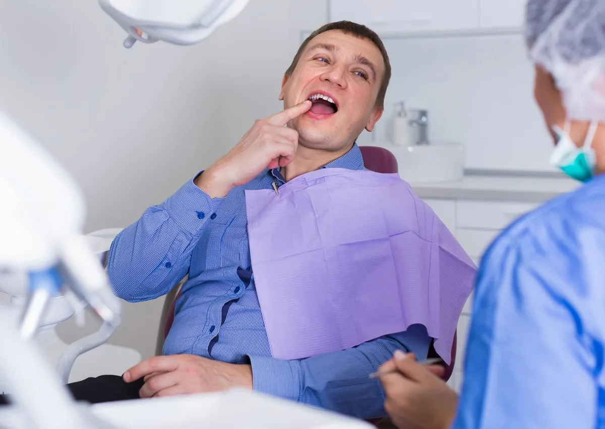 Patient pointing to a tooth during a dental visit while discussing what cavities can look like.
